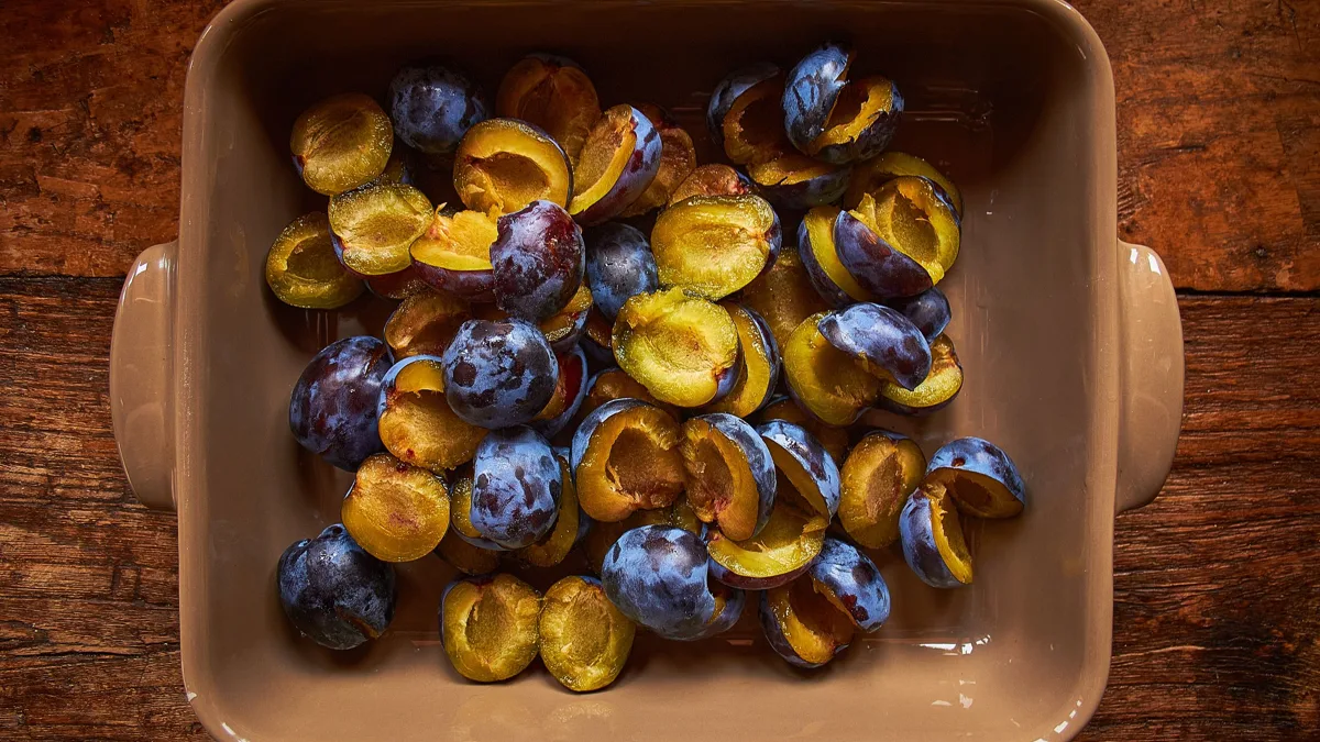 Clafoutis doré aux prunes dans un plat beurré, texture moelleuse et fruits bien alignés